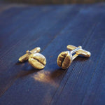 resting on a wooden board sits two sterling silver coffee bean cuff links