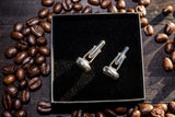 surrounded by coffee beans sits in a jewellery box without the lid, two sterling silver coffee bean cuff links