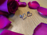 facing the camera is a pair of sterling silver heart earrings