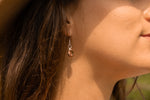 a close up of the model wearing a pair of red bronze coffee bean earrings