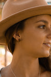 facing right and smiling the model is displaying a set of red bronze stud coffee bean earrings