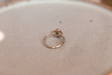 A close up shot from behind of a sterling silver coffee bean ring on a ceramic plate