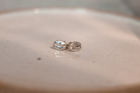 resting on a ceramic is a pair of sterling silver coffee bean earrings