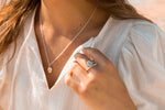 with her hand angled on her linen shirt the model is wearing the sterling silver coffee bean ring while wearing her coffee bean necklace